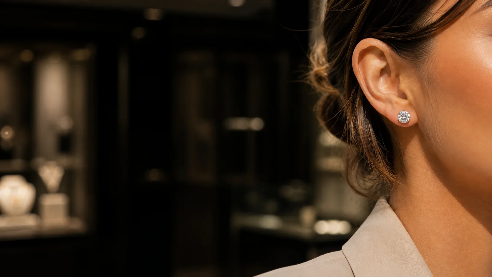 Woman wearing a classic round diamond stud in a softly lit jewelry showroom
